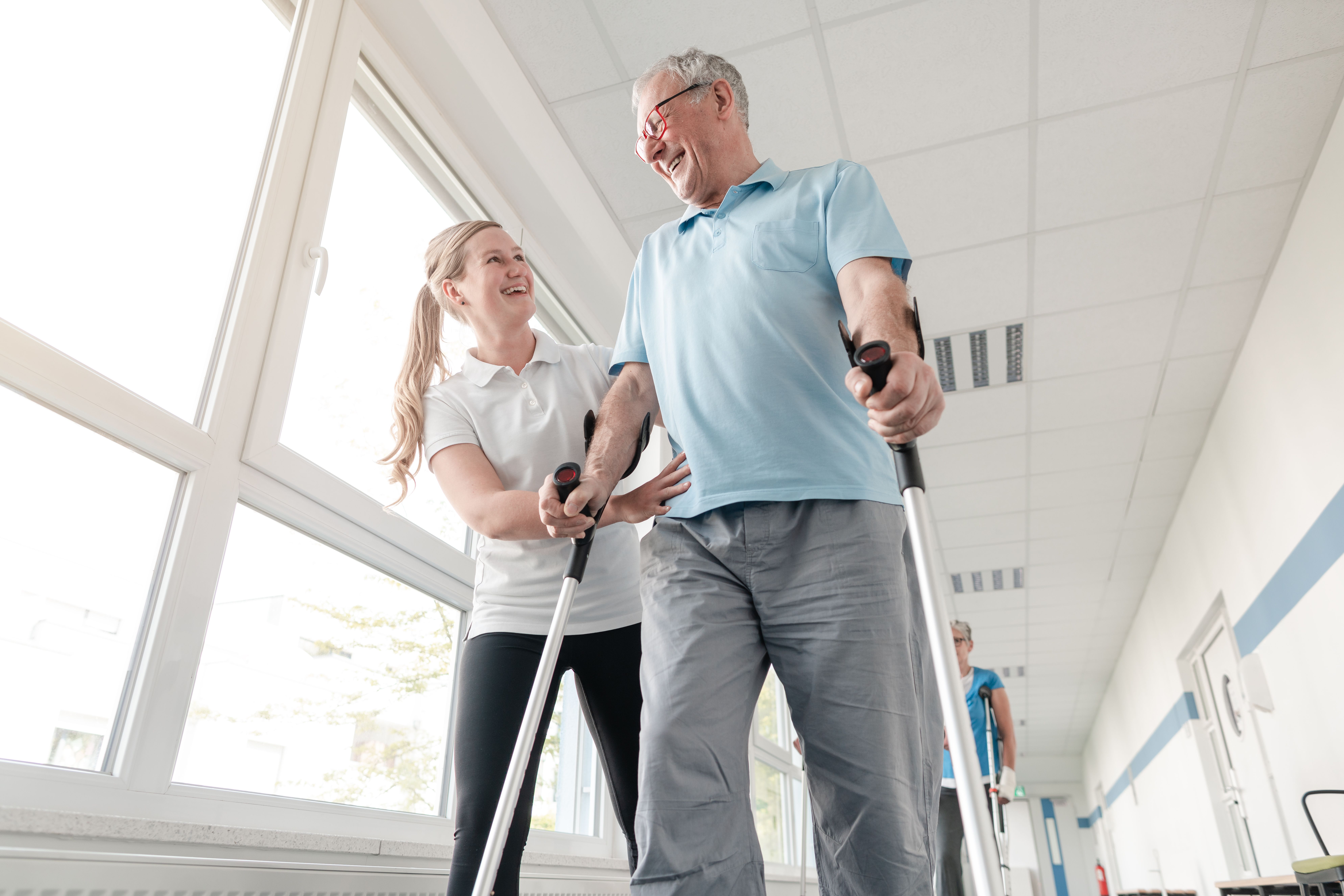 Senior mit Krücken in der Physiotherapie mit Therapeutin